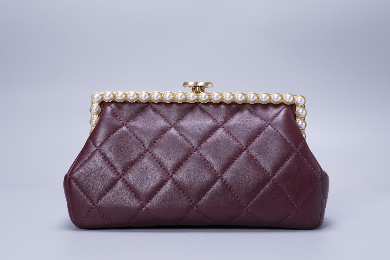 Bolsa de mão vinho com acabamento matelassê e fecho decorativo
